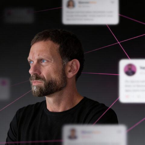 Josip trägt ein schwarzes T-Shirt und schaut nach links, vor einem dunklen Hintergrund mit pinken Verbindungslinien und unscharfen Profilkarten